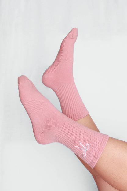 Pink socks with a logo on a light gray background