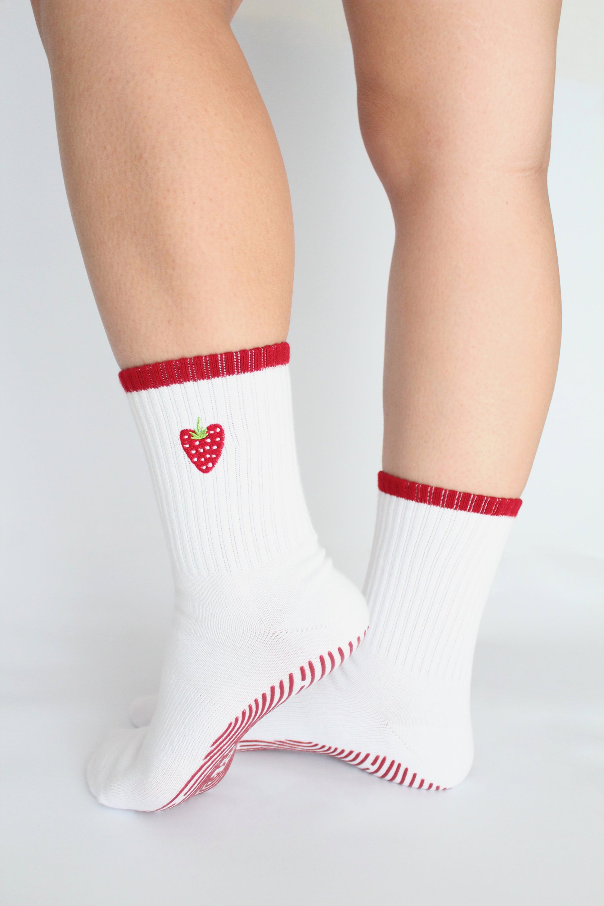White socks with red heart design and trim worn by a person on a light gray background