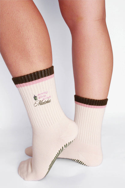 Beige socks with brown and pink accents worn by a person on a white background