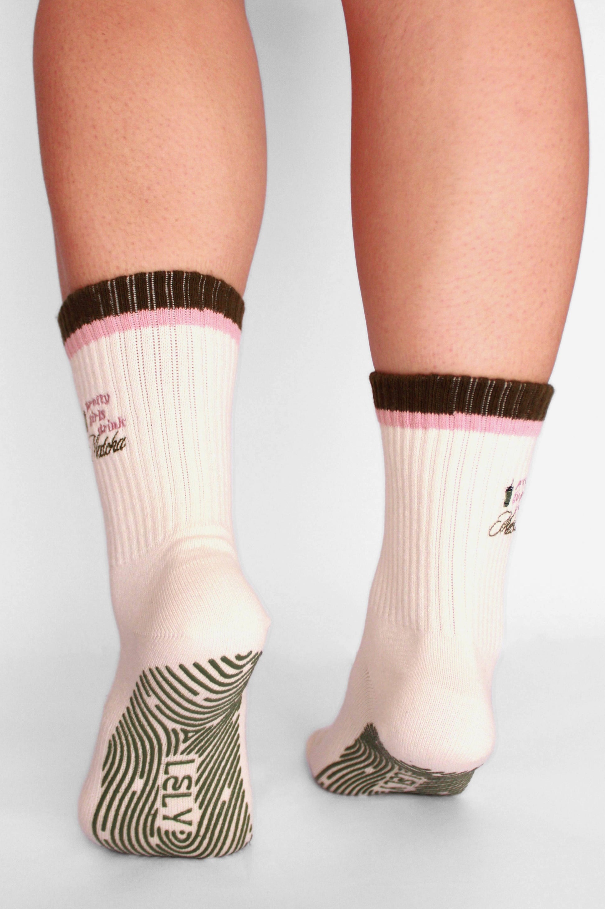 White socks with brown and pink accents worn by a person on a light gray background